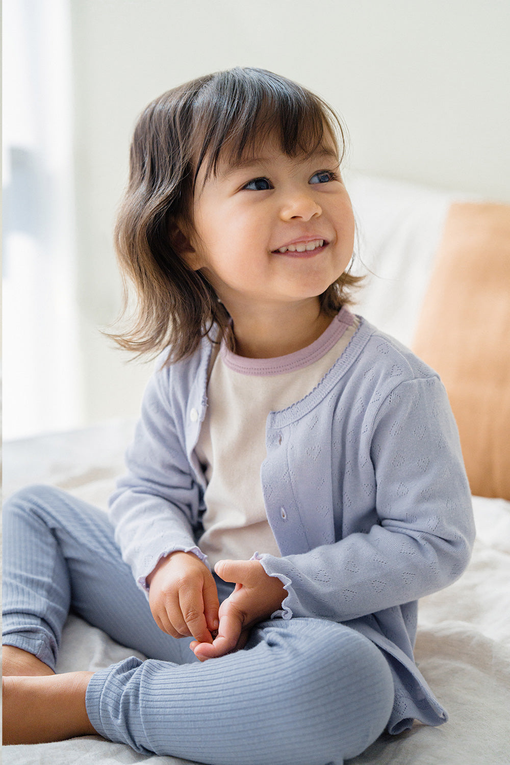 Toddler girl smiling in Avauma Haze Heart Cardigan, soft lavender baby cardigan perfect for cozy everyday outfits. Toddler girl smiling in Avauma Haze Heart Cardigan, soft lavender baby cardigan perfect for cozy everyday outfits.