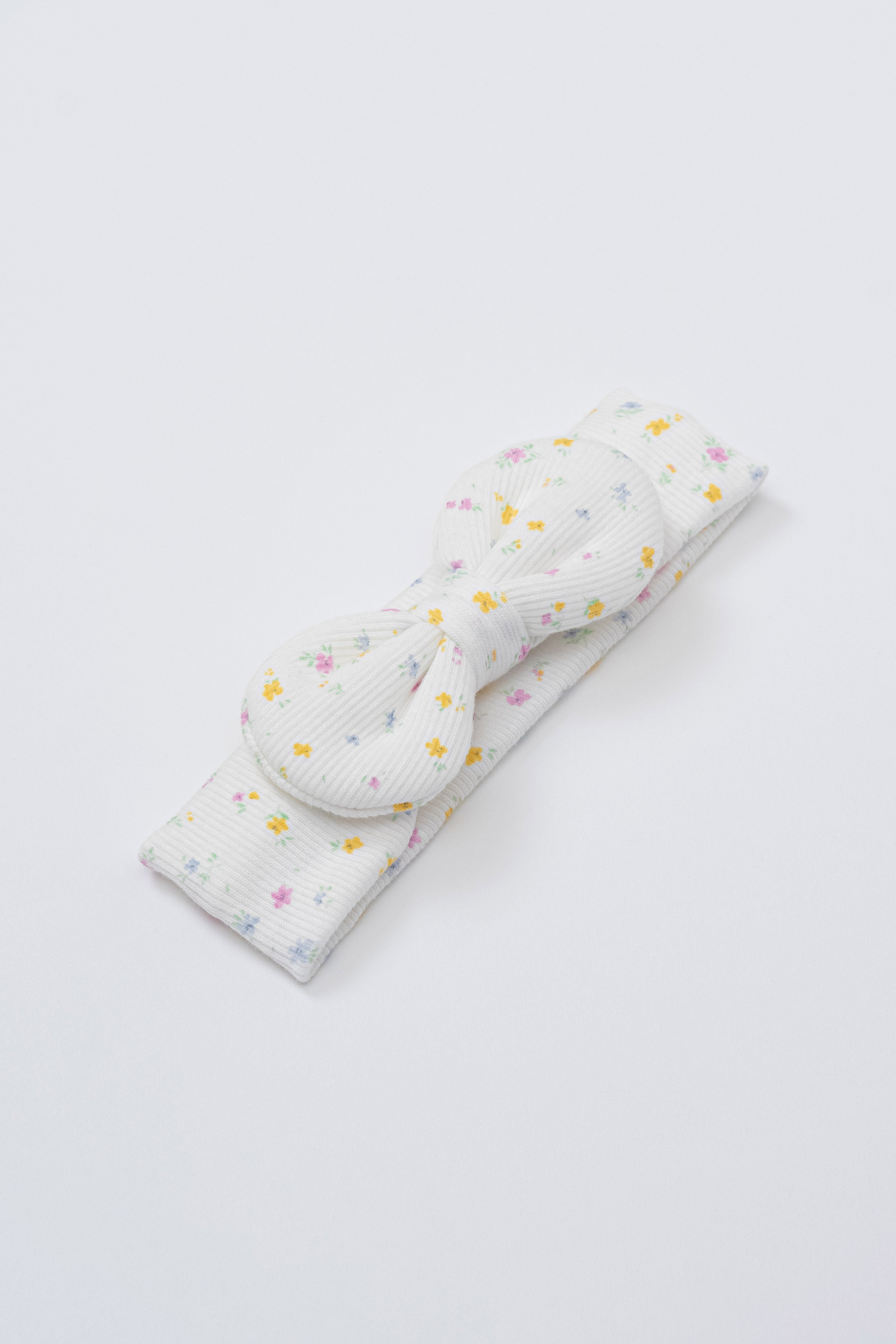 Avauma Lovely Bloom Headband in Butter Garden, featuring multicolor floral print on soft ribbed white fabric with centered bow Avauma Lovely Bloom Headband in Butter Garden, featuring multicolor floral print on soft ribbed white fabric with centered bow