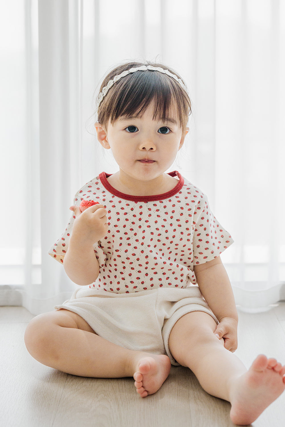 Toddler girl wearing Avauma Mellow Pop Ivory Berry Set, sitting comfortably and looking towards camera Toddler girl wearing Avauma Mellow Pop Ivory Berry Set, sitting comfortably and looking towards camera