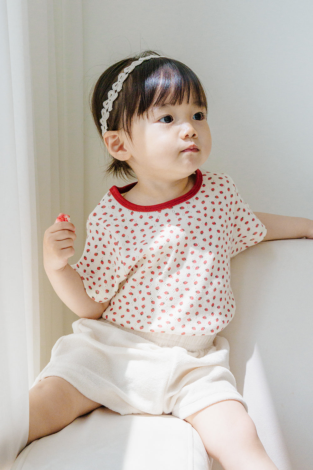 Toddler girl in Avauma Ivory Berry T-Shirt and Shorts, relaxing on sofa with natural sunlight Toddler girl in Avauma Ivory Berry T-Shirt and Shorts, relaxing on sofa with natural sunlight