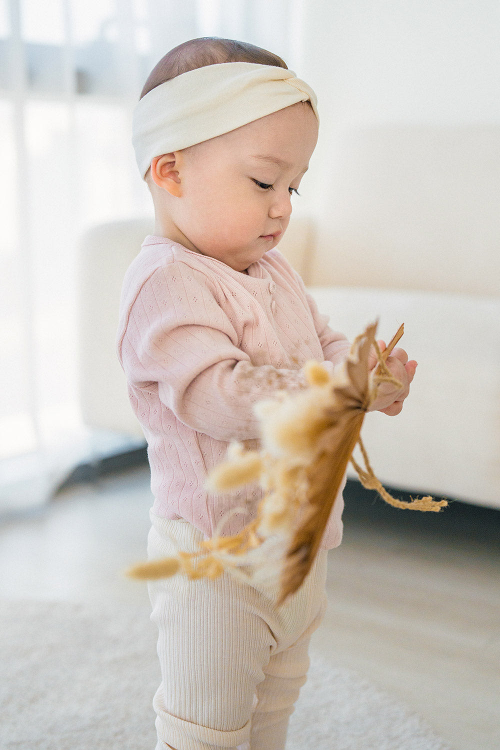 Baby looking at a toy – wearing the Avauma Peach Glow Set in Pale Peach, featuring a knit top and stretchy leggings for enhanced mobility Baby looking at a toy – wearing the Avauma Peach Glow Set in Pale Peach, featuring a knit top and stretchy leggings for enhanced mobility