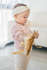 Baby looking at a toy – wearing the Avauma Peach Glow Set in Pale Peach, featuring a knit top and stretchy leggings for enhanced mobility Baby looking at a toy – wearing the Avauma Peach Glow Set in Pale Peach, featuring a knit top and stretchy leggings for enhanced mobility