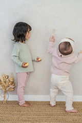 A child in the Avauma Peach Glow Set in Soft Sage standing alongside another baby in a different color set – a versatile sibling look available in multiple shades A child in the Avauma Peach Glow Set in Soft Sage standing alongside another baby in a different color set – a versatile sibling look available in multiple shades