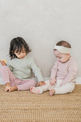 Two children sitting side by side in the Avauma Peach Glow Set in Soft Sage and a pink-toned set – a neat design and cohesive styling for a comfy, adorable kids’ outfit Two children sitting side by side in the Avauma Peach Glow Set in Soft Sage and a pink-toned set – a neat design and cohesive styling for a comfy, adorable kids’ outfit