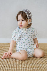 Baby girl wearing Avauma Petit Ruffle Bluebell short sleeve set, sitting on a beige carpet.
Baby girl wearing Avauma Petit Ruffle Bluebell short sleeve set, sitting on a beige carpet.