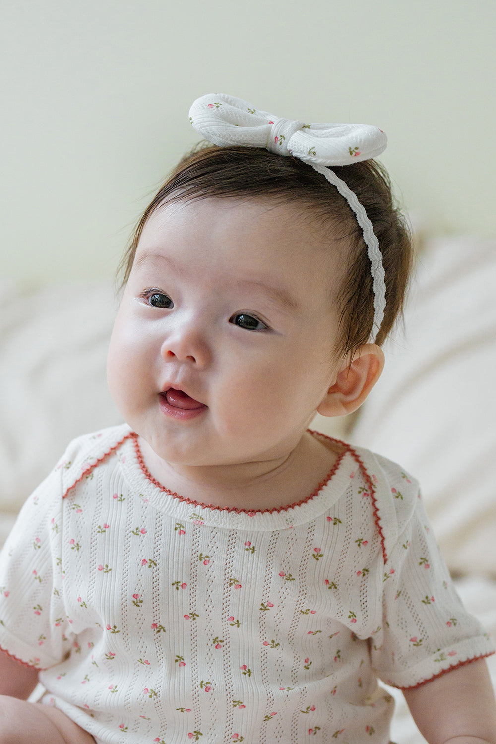 Baby girl sitting up wearing Avauma Petite Garden Headband in Rose Garden, paired with matching floral outfit Baby girl sitting up wearing Avauma Petite Garden Headband in Rose Garden, paired with matching floral outfit
