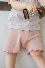 Close-up of baby pink ribbed shorts with lettuce hem detail, part of a floral baby summer set.
Close-up of baby pink ribbed shorts with lettuce hem detail, part of a floral baby summer set.