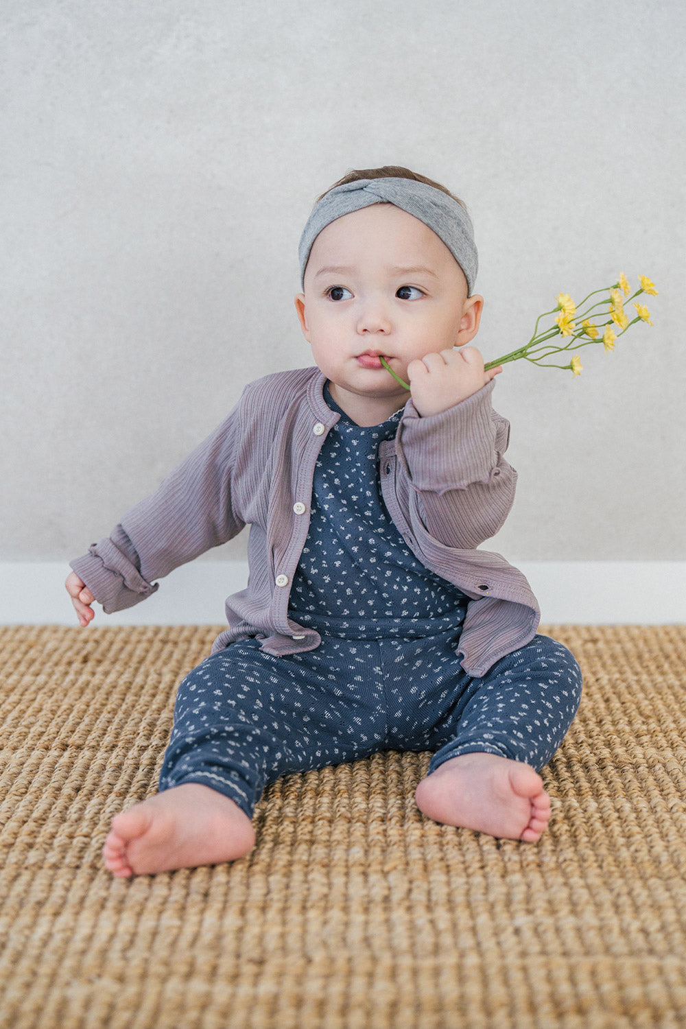 Avauma ribbed baby cardigan in Ash Beige, soft cotton sweater layered over floral jumpsuit for infants Avauma ribbed baby cardigan in Ash Beige, soft cotton sweater layered over floral jumpsuit for infants