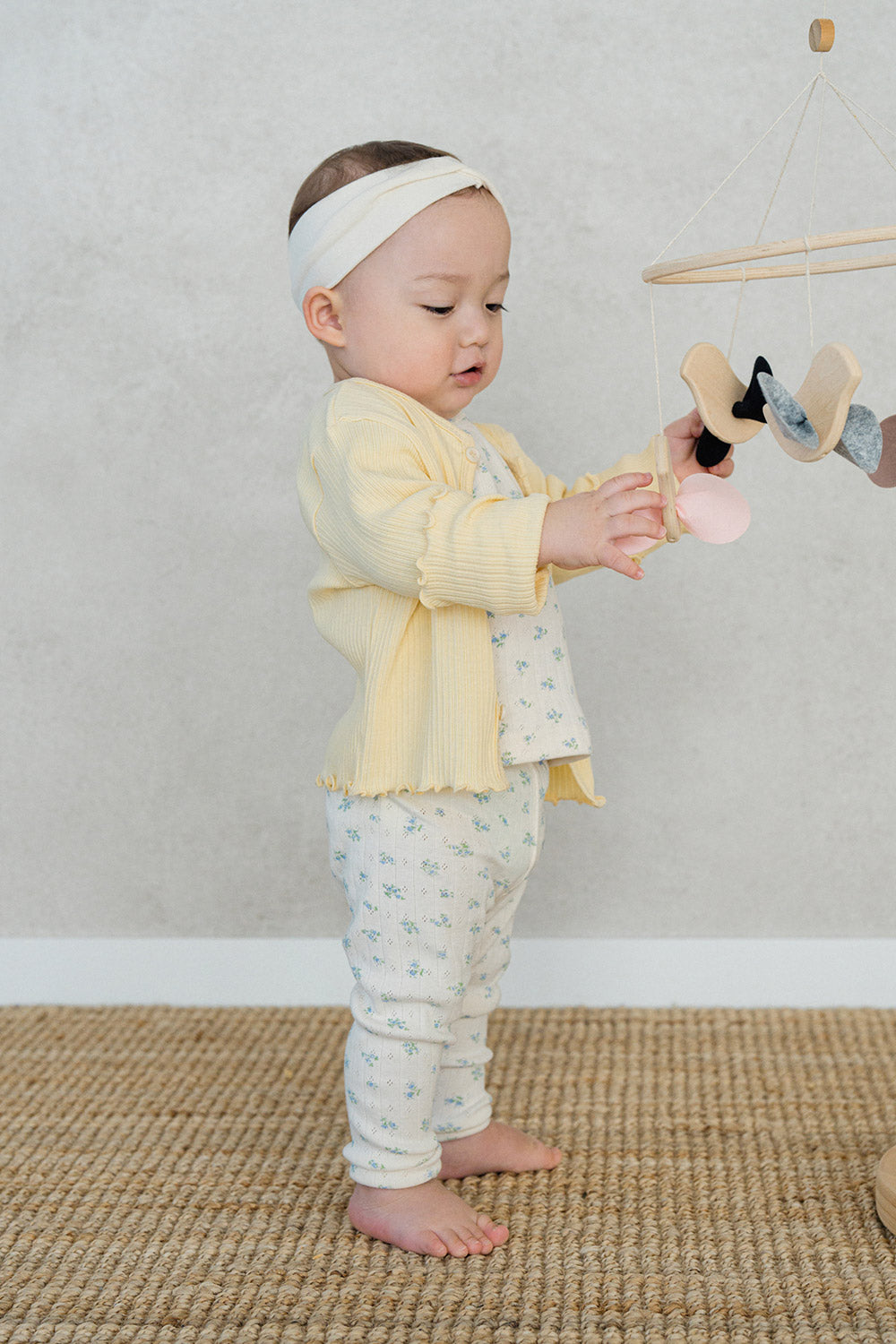 Infant girl in Avauma butter yellow cardigan and floral baby pants, cozy and cute baby outfit for playtime Infant girl in Avauma butter yellow cardigan and floral baby pants, cozy and cute baby outfit for playtime
