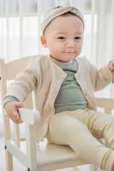 Close-up of Avauma baby cardigan in off white, soft ribbed texture and natural buttons Close-up of Avauma baby cardigan in off white, soft ribbed texture and natural buttons
