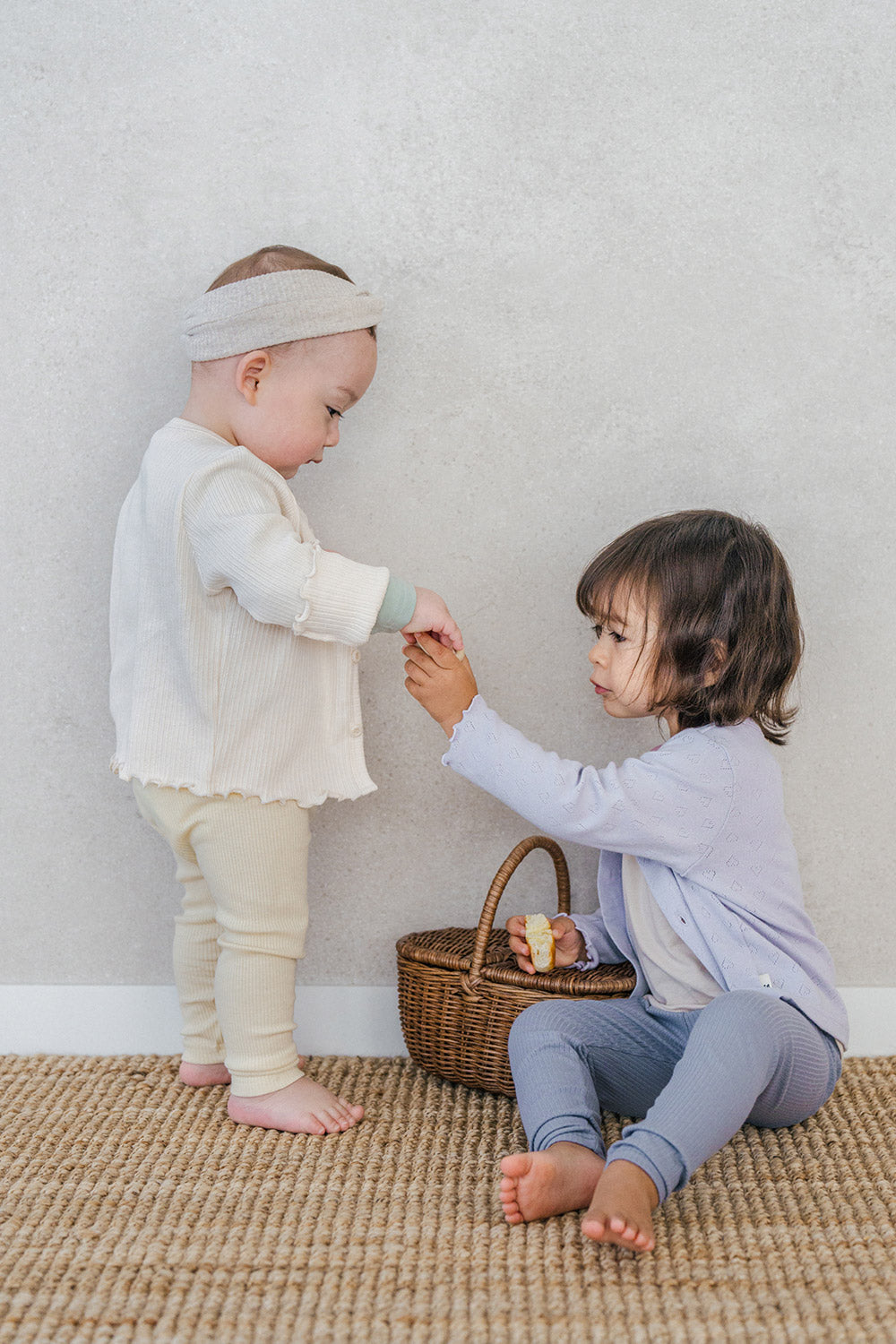 Avauma toddler girl and baby in cardigans sharing snacks, spring sibling outfit look Avauma toddler girl and baby in cardigans sharing snacks, spring sibling outfit look