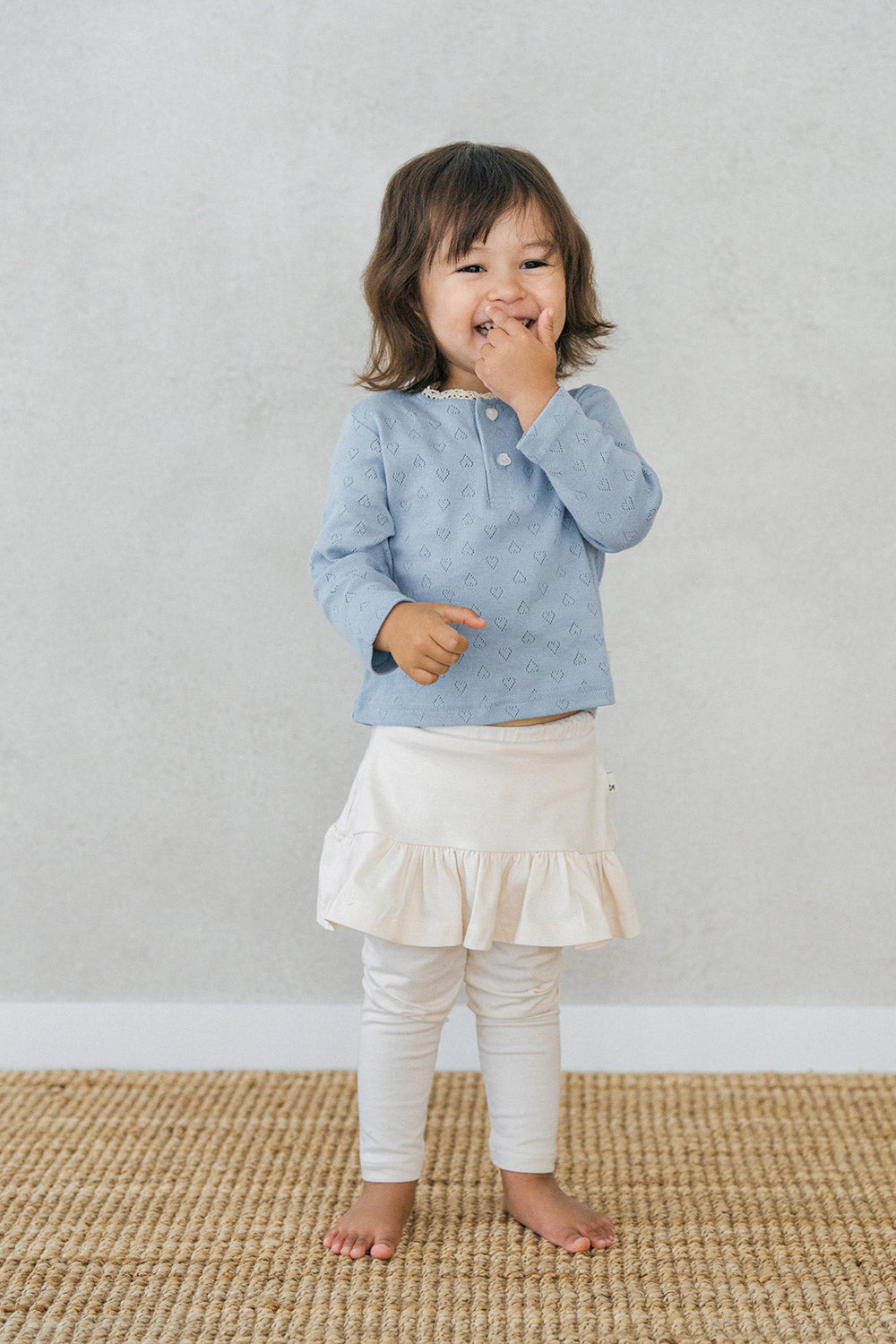 Full-body shot of a baby girl in Avauma milky white skirt leggings with a delicate ruffle hem โ modern and cozy infant outfit Full-body shot of a baby girl in Avauma milky white skirt leggings with a delicate ruffle hem โ modern and cozy infant outfit