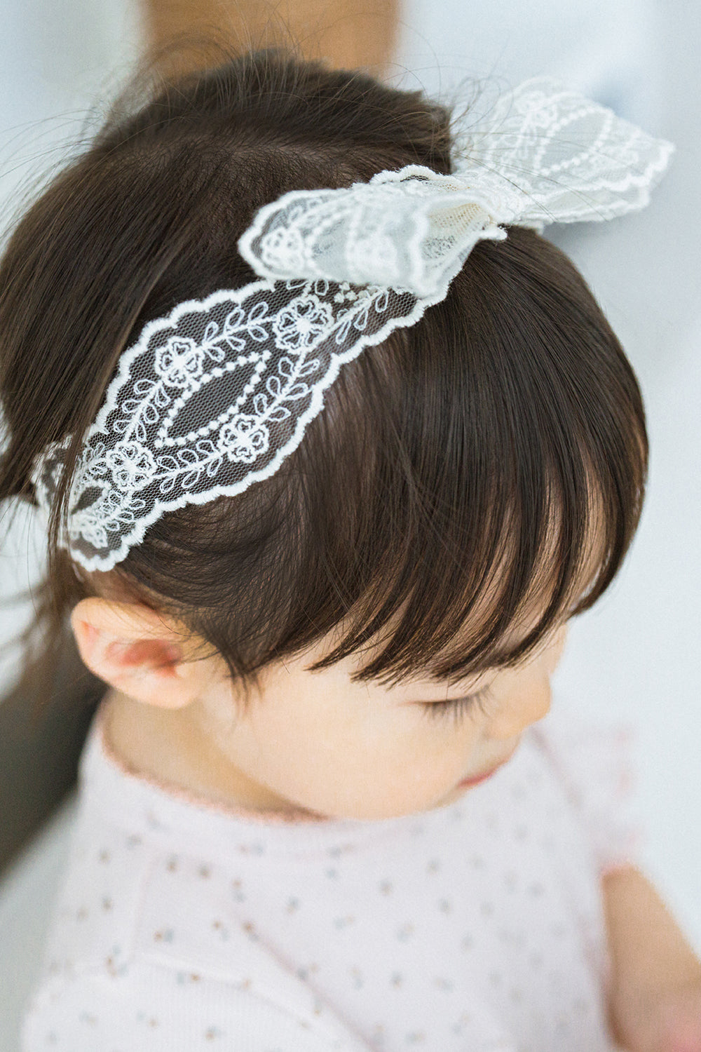 Toddler girl wearing Avauma Rumiere Ribbon Band, top view showing lace detail over bangs Toddler girl wearing Avauma Rumiere Ribbon Band, top view showing lace detail over bangs