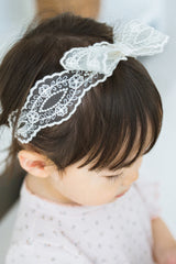 Toddler girl wearing Avauma Rumiere Ribbon Band, top view showing lace detail over bangs Toddler girl wearing Avauma Rumiere Ribbon Band, top view showing lace detail over bangs