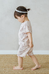 A toddler girl walking indoors, dressed in Avauma Sienna Rose Rosy Powder floral summer set with cute frilled sleeves and shorts. A toddler girl walking indoors, dressed in Avauma Sienna Rose Rosy Powder floral summer set with cute frilled sleeves and shorts.