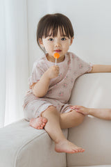 Close-up of a toddler wearing Avauma Sienna Rose Rosy Powder short sleeve set, showing the delicate pink floral fabric and wavy edges. Close-up of a toddler wearing Avauma Sienna Rose Rosy Powder short sleeve set, showing the delicate pink floral fabric and wavy edges.