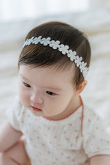 Smiling toddler with pigtails wearing Avauma White Garden Band headband in Pure White Smiling toddler with pigtails wearing Avauma White Garden Band headband in Pure White