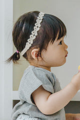Toddler girl in gray knit outfit wearing Avauma White Garden Band headband in Cream Beige Toddler girl in gray knit outfit wearing Avauma White Garden Band headband in Cream Beige