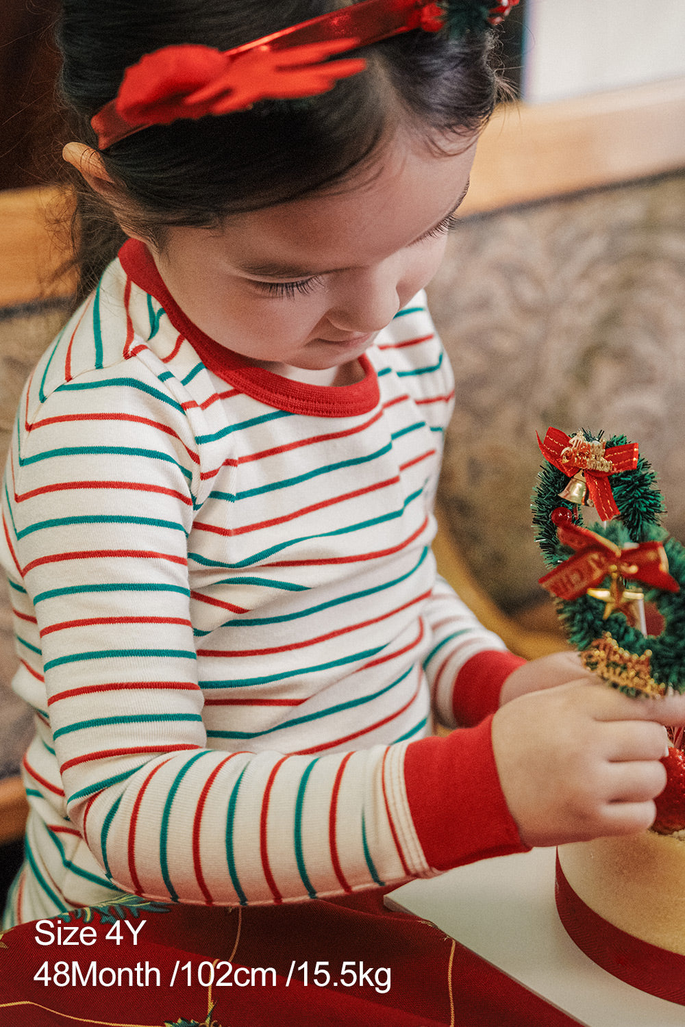 Close-up of child wearing AVAUMA Holiday Long Sleeve Pajama Set - Candy Stripe Redcuff, red and green striped pattern

