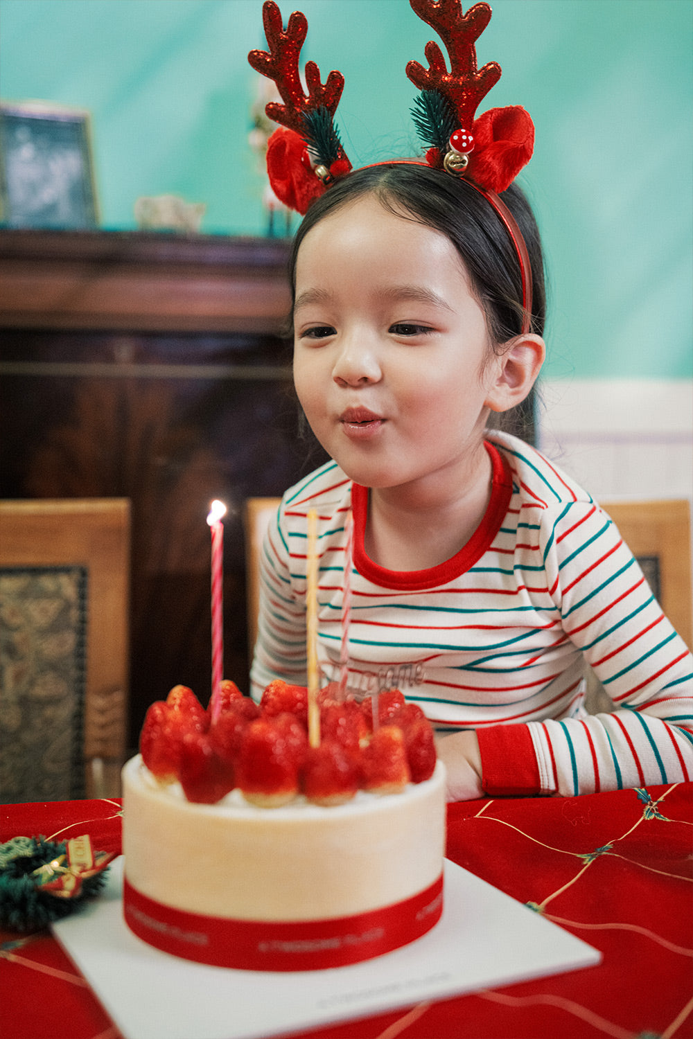 Child celebrating holiday with cake, dressed in AVAUMA Holiday Long Sleeve Pajama Set - Candy Stripe Redcuff

