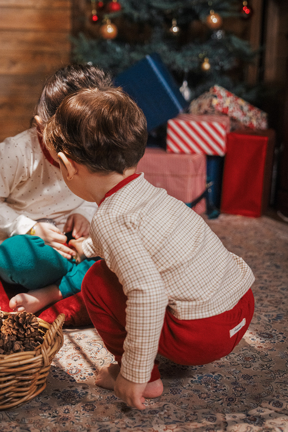 Kids laughing and holding red Christmas ornaments while wearing Avauma Holiday Pajama Sets in festive red and green

