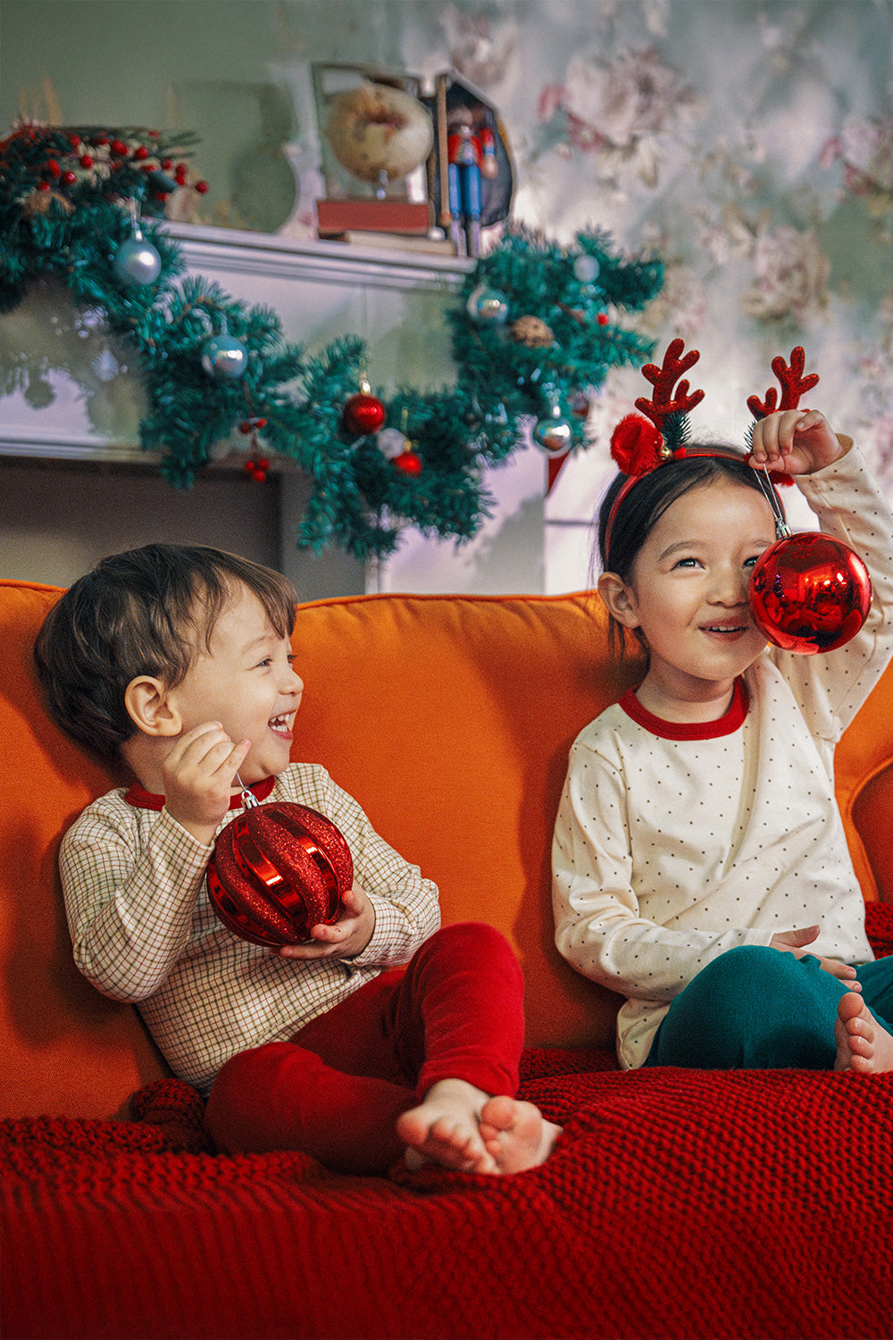 Joyful children with Christmas decor in Avauma Cranberry Check Pajama Set, creating holiday memories on a vibrant couch

