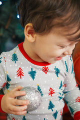 Baby sitting on orange sofa with red ornament, wearing AVAUMA Holiday Long Sleeve Pajama Set - Happy Tree