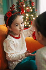 "Holiday-themed baby pajama set in cream with small polka dots, red trim, and cozy green pants. Perfect for a warm Christmas morning."