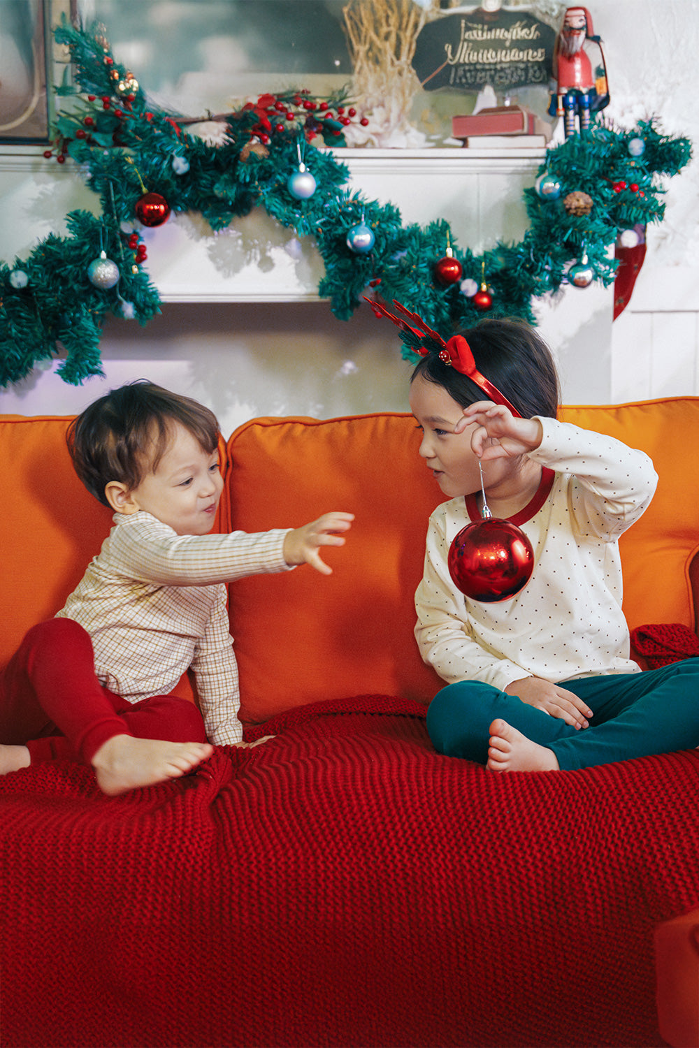 Two toddlers in Avauma holiday pajamas, with one wearing polka dot set and the other in cranberry check pattern. Perfect for holiday celebrations.