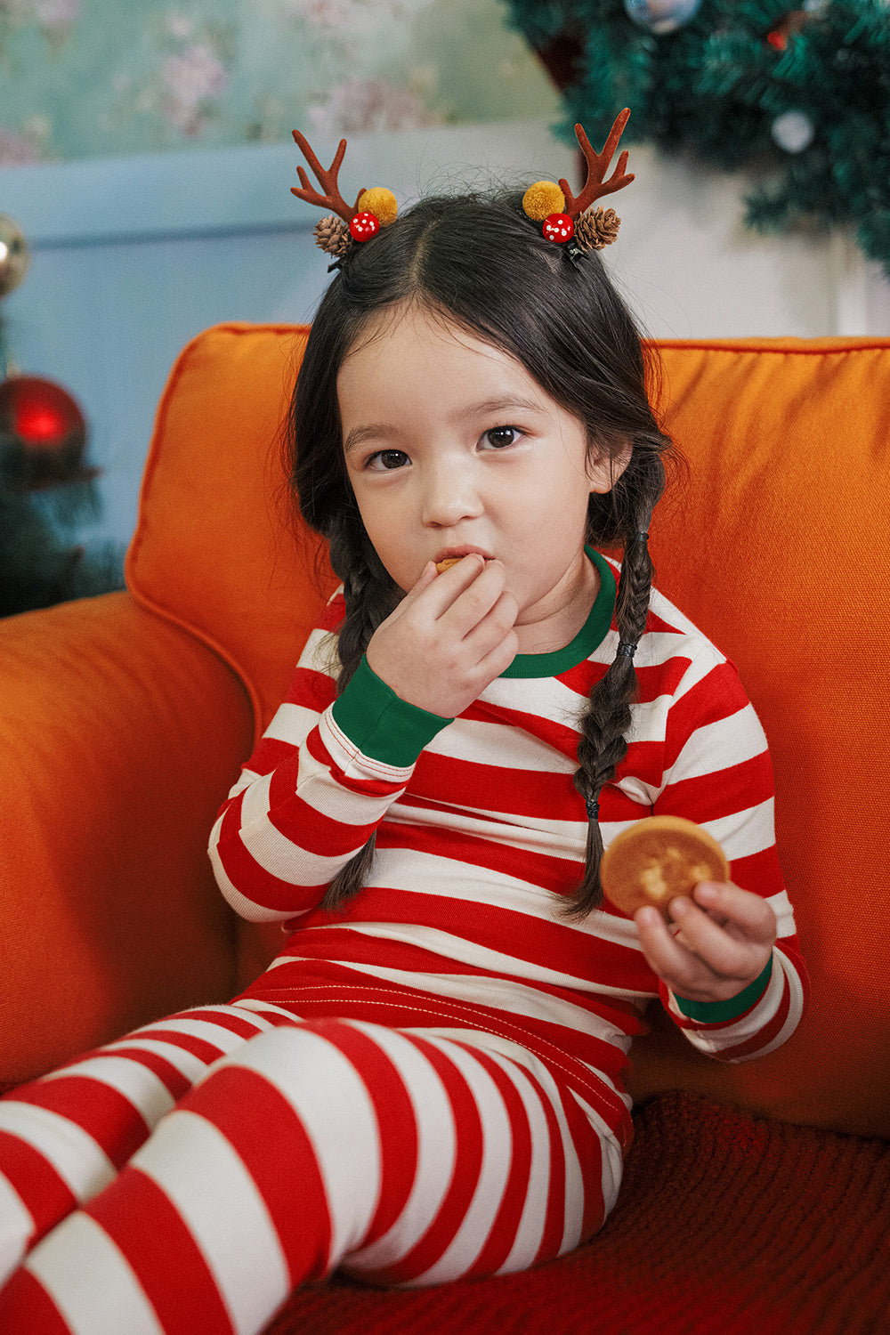 Child enjoying a Christmas snack while wearing AVAUMA Holiday Long Sleeve Pajama Set - Jolly Stripe Greencuff

