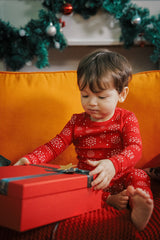 Baby with red gift box, dressed in AVAUMA Holiday Long Sleeve Pajama Set - Snowflake, red with snowflake pattern

