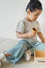 Baby girl sitting in Avauma Sky Blue pleated summer pants indoors