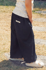 Side view of Avauma Soft Black pleated toddler pants outdoors