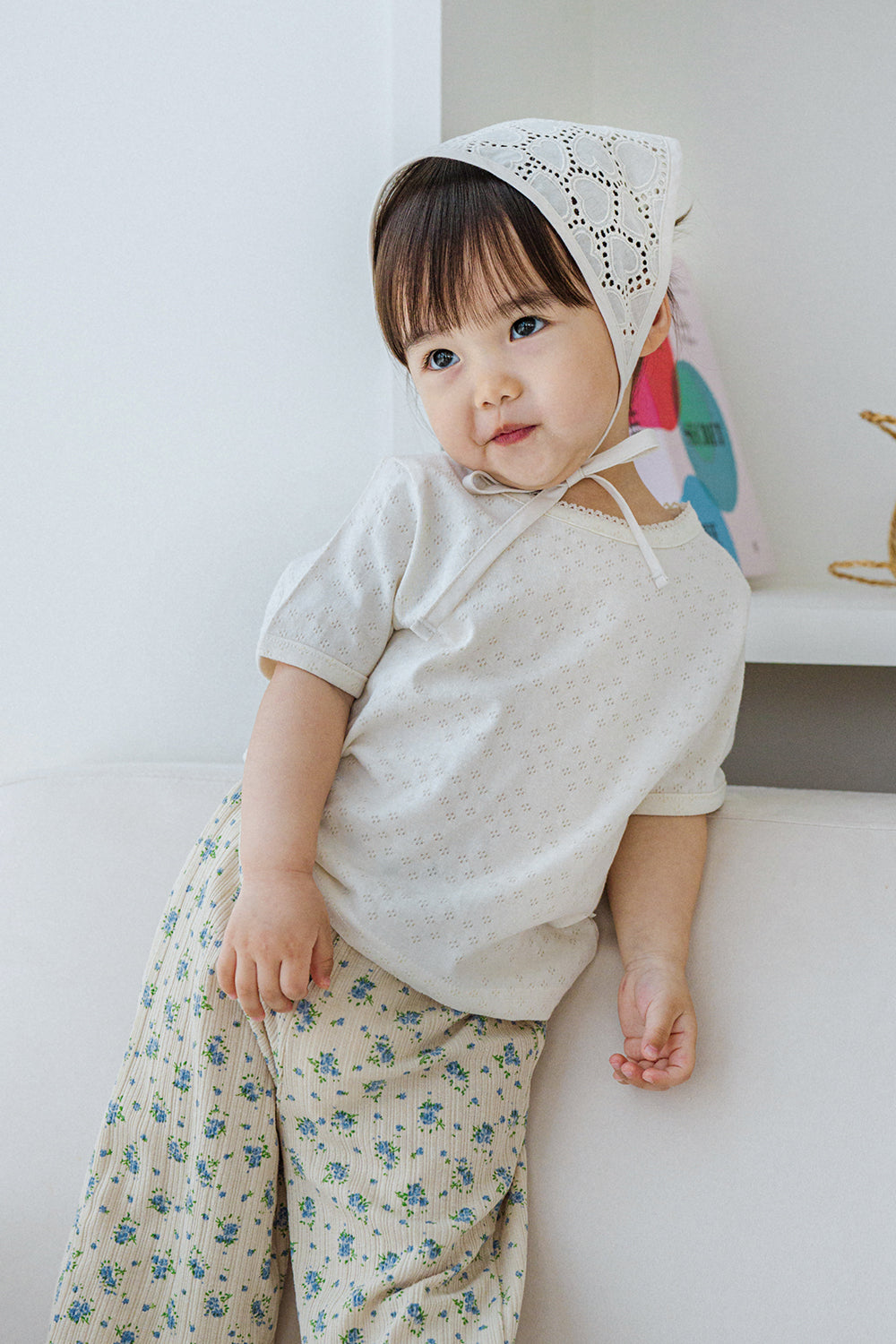 Toddler wearing milk pearl short sleeve baby shirt with lace trim and floral pants, tilting head – Avauma


