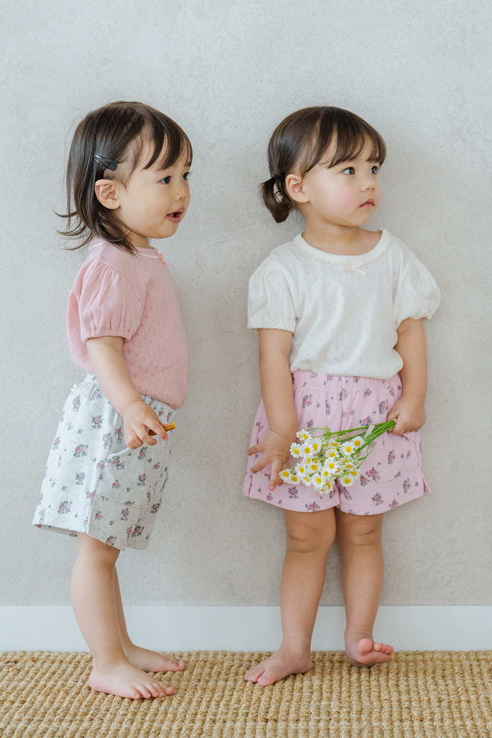 Two Toddlers Wearing Avauma Fluffy Garden Shorts in Peach Mood and Melange Berry, Floral Pattern Cotton Shorts

