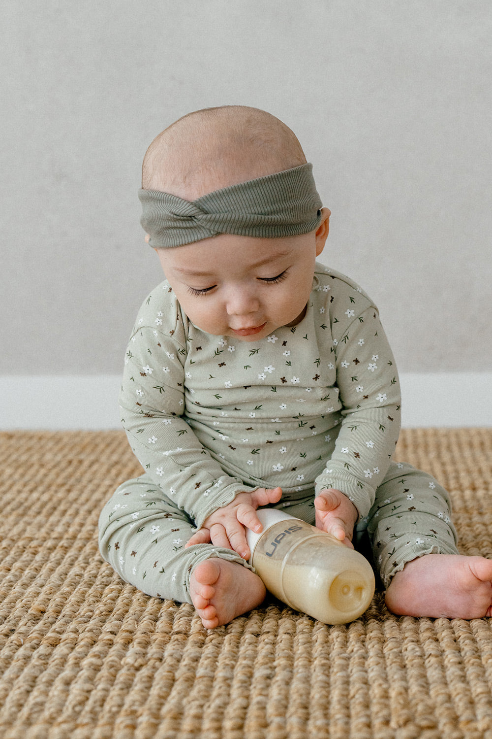 Baby playing while wearing Avauma Mini Fleur Long Sleeve Set - Frill Ellabeige, a comfortable and cute pajama set with a floral print and frill details.