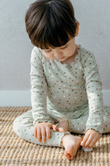 Toddler sitting in Avauma Mini Fleur Long Sleeve Set - Frill Ellabeige, a floral beige pajama set with frill accents, designed for warmth and comfort.