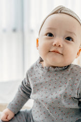 Close-up of baby wearing Avauma Eyelet Bloom Setup - Gray Bloom, highlighting the floral print and soft fabric of the gray pajama set.