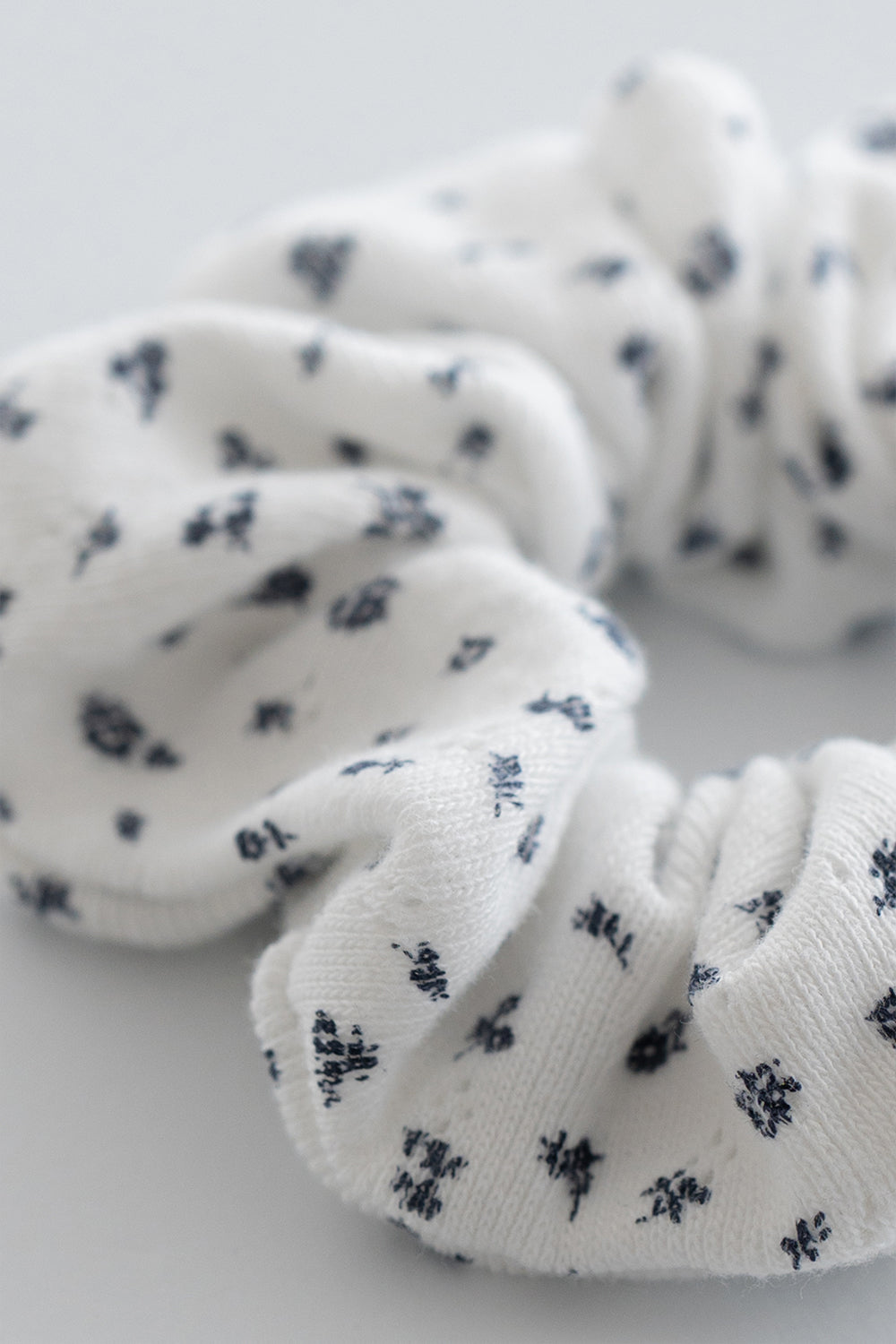 Close-up of indigo whisper scrunchie in white ribbed fabric with navy floral design – Avauma

