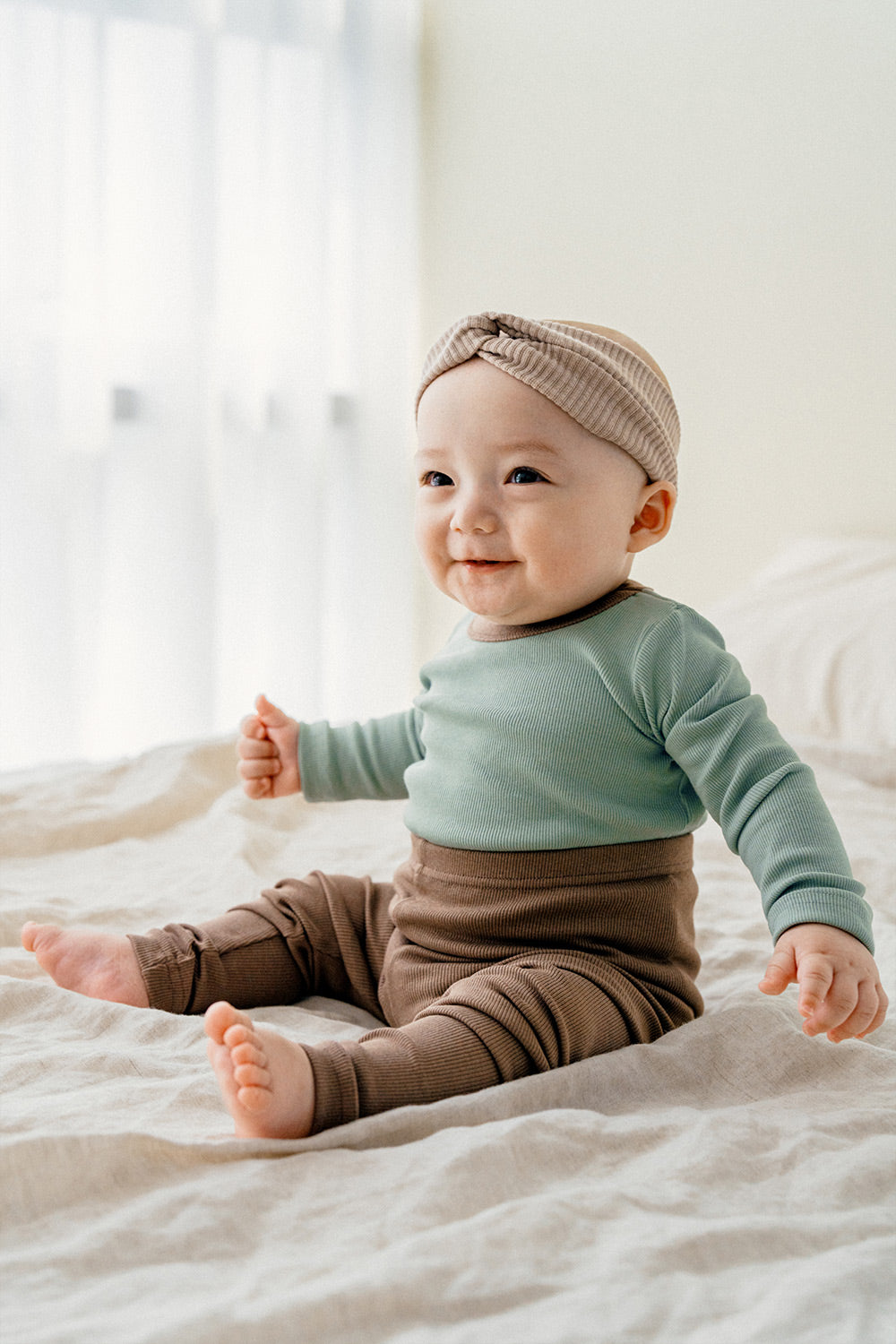 Happy baby wearing Avauma's Coco Classic Long Sleeve Set in Applemint bun color - a stylish and comfortable loungewear set for babies, perfect as baby sleepwear or playtime pajamas