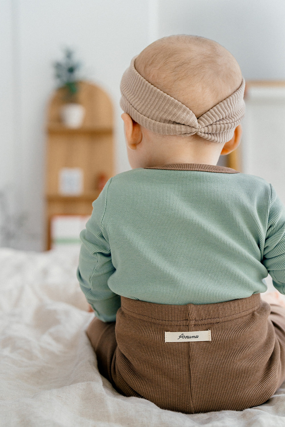 Back view of a baby wearing Avauma's Coco Classic Long Sleeve Set in Applemint bun color - soft green top with brown pants, ideal for stylish baby sleepwear and comfortable loungewear