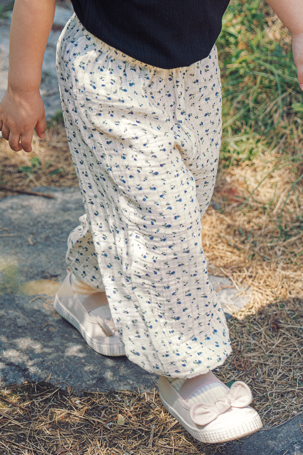 A happy young girl wearing Avauma 100% cotton floral print pants, a lightweight summer breeze jogger suitable for active toddlers aged 1 to 3.