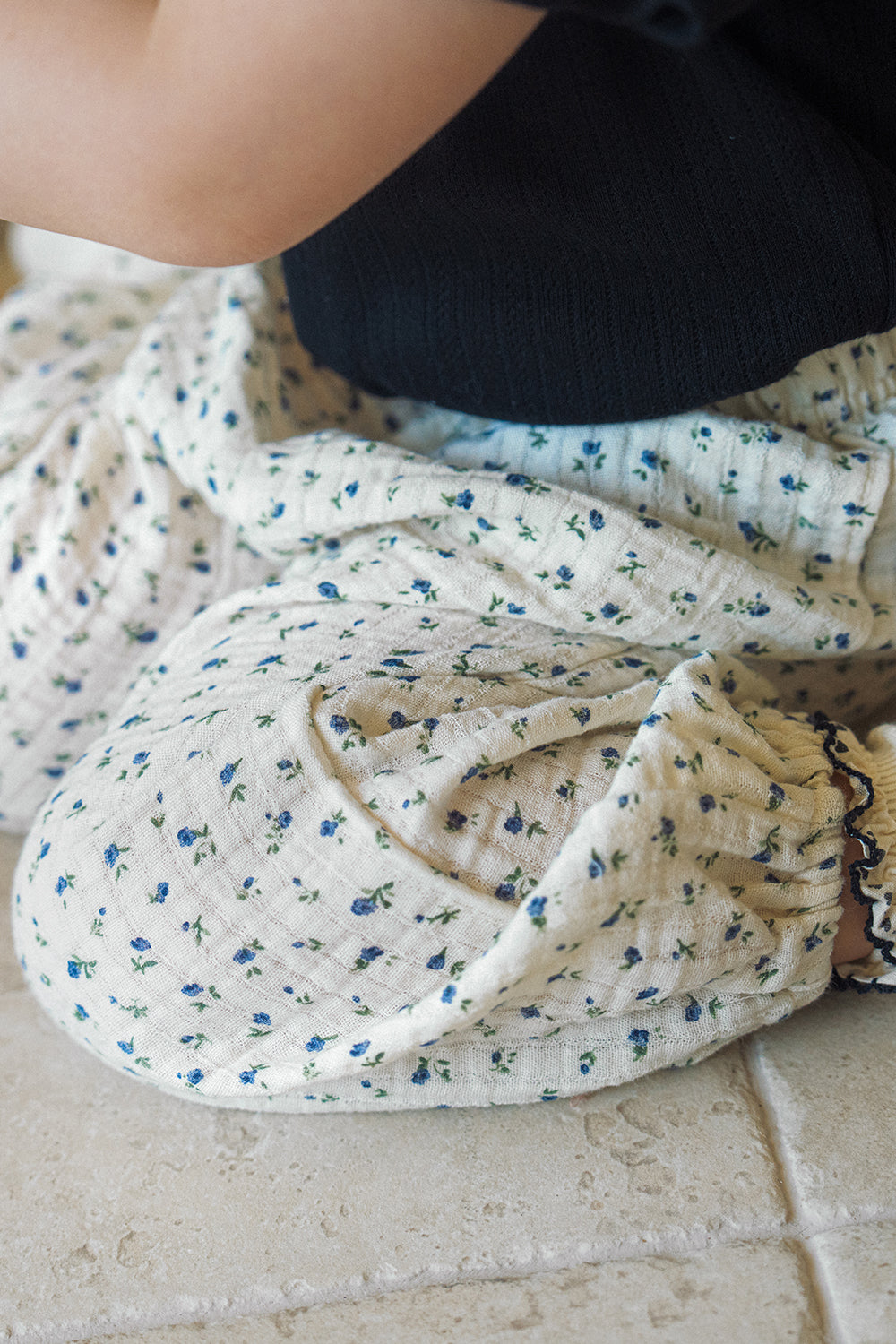 Detailed close-up texture of Avauma 100% cotton gauze muslin fabric with a blue floral pattern, high-quality material for children's clothing.