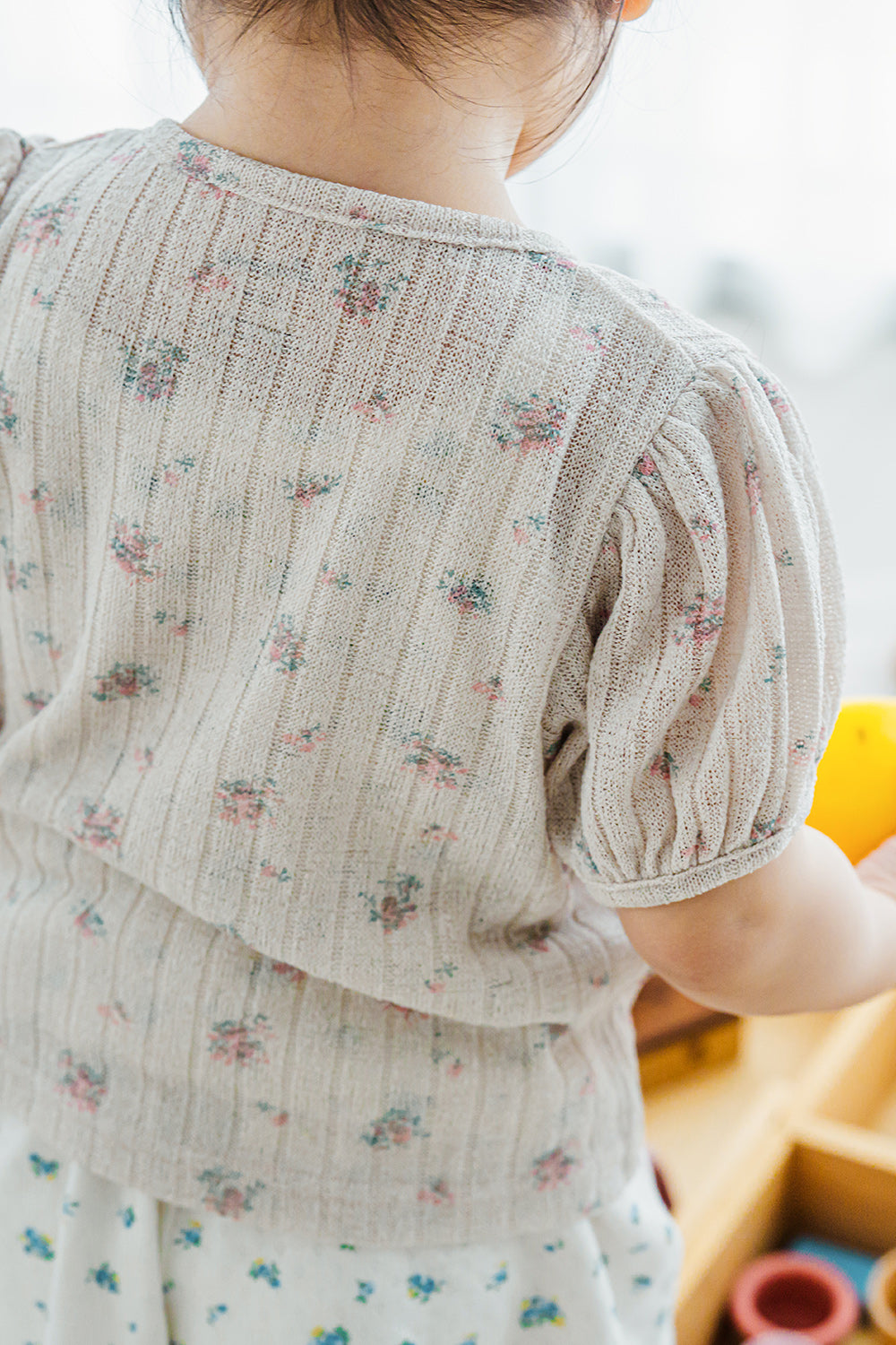 Back view of child wearing Avauma Buttercumin cardigan in sand floral.

