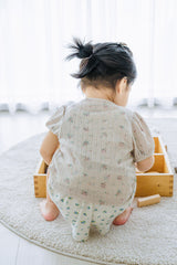 Baby playing with wooden blocks in Avauma Buttercumin cardigan, sand floral pattern.

