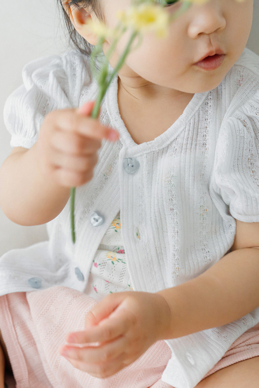 Close-up of toddler holding a flower in Avauma apricot daisy tank top