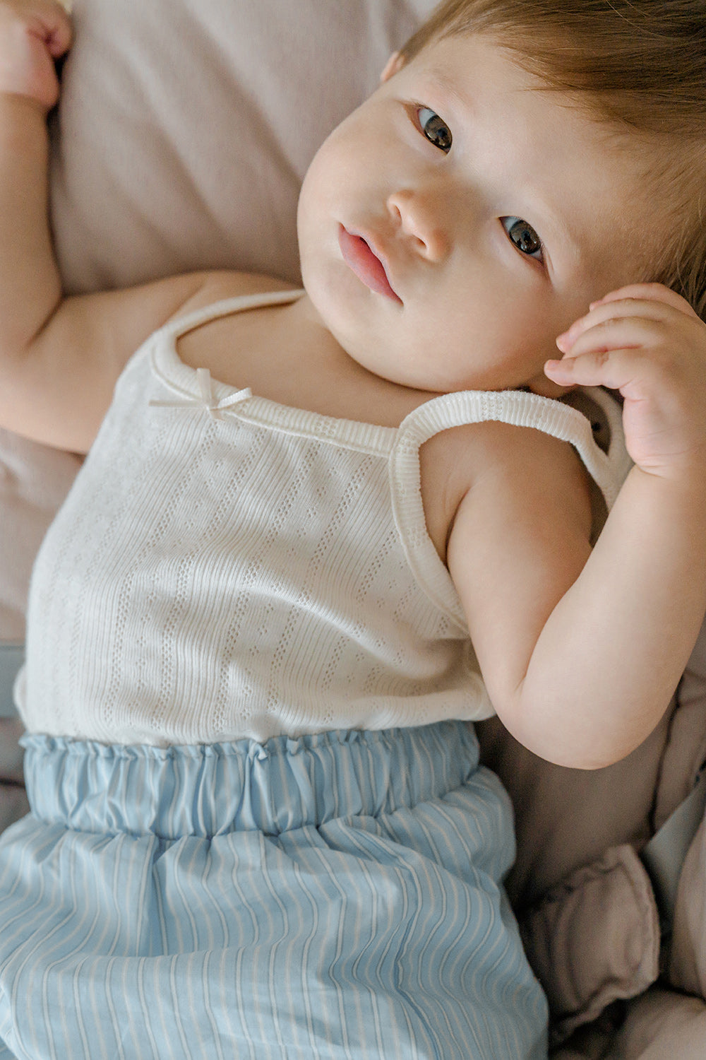 Baby lying down in Avauma pure vanilla sleeveless top and blue shorts – soft and cozy dailywear
