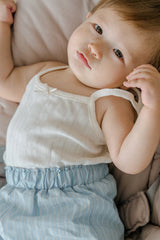 Baby lying down in Avauma pure vanilla sleeveless top and blue shorts – soft and cozy dailywear
