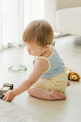 Baby sitting and playing in Avauma pale lime sleeveless top and shorts
