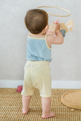 Rear view of baby standing by a play set in Avauma pale lime sleeveless set
